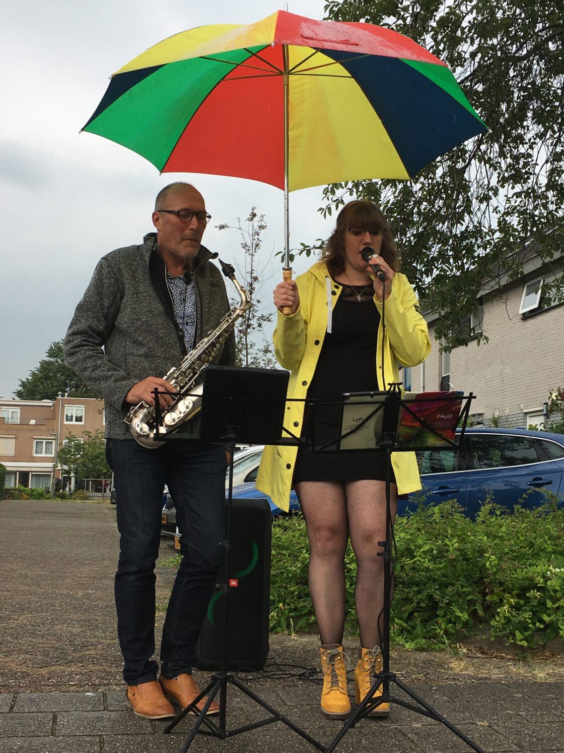 saxofonist en zangeres onder paraplu op straat